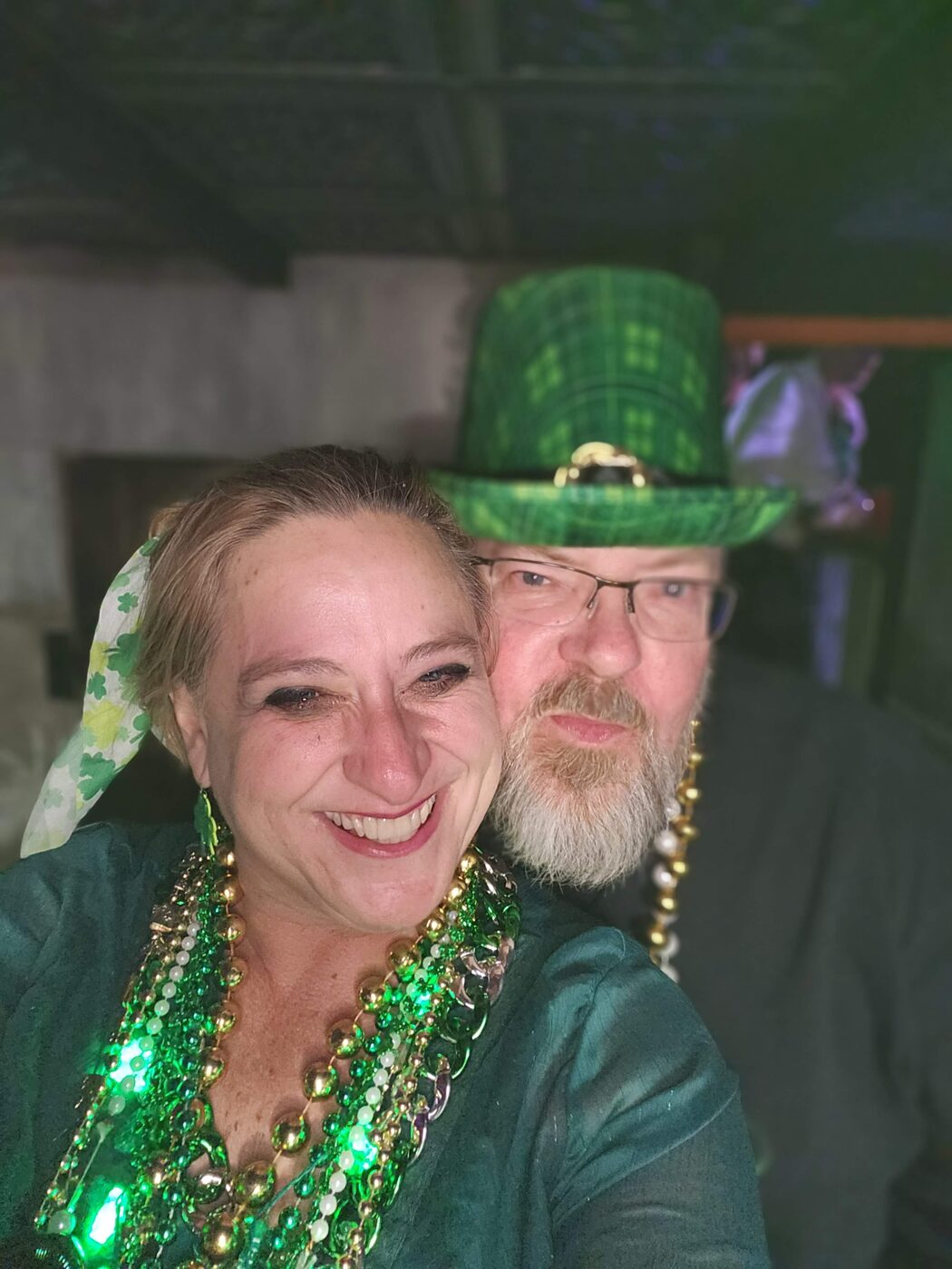 Krewe member in a green top hat with a friend